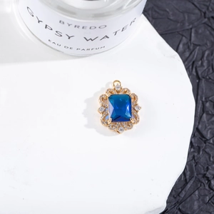 Detalle macro del colgante de gema azul rectangular con halo de circonitas y oro