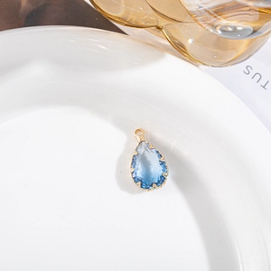 Détail macro d'un pendentif en cristal de goutte d'eau bleu avec monture dorée