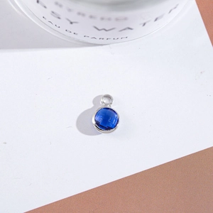 Macro detail of a round blue faceted crystal pendant in a silver metal bezel setting