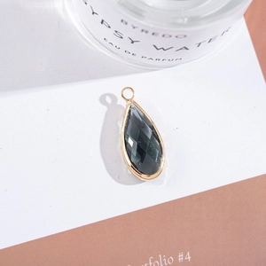 Detailed view of dark grey teardrop crystal pendant in a gold-plated copper frame