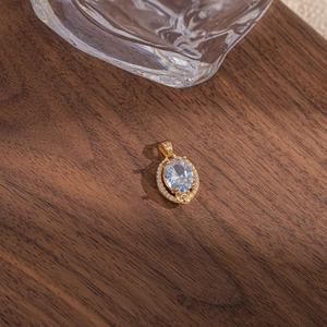 Vue macro du pendentif ovale doré avec grand cristal central et détails en zircons