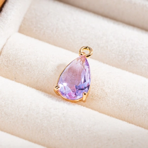 Vue macro d'un pendentif en cristal lavande en forme de goutte et monture dorée