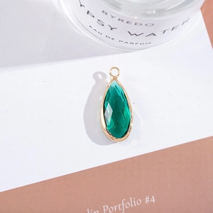 Macro detail of dark green waterdrop crystal pendant with elegant gold plated metal edging