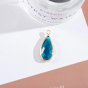Detailed view of teardrop faceted blue crystal pendant with gold plating and ring hook