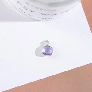 Macro shot of silver-edged round purple crystal pendant for DIY jewelry making and crafts
