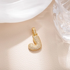 Macro detail of gold-plated hip hop letter J pendant with micro-pave cubic zirconia