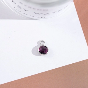 Macro shot of silver-set round faceted burgundy crystal pendant with detailed metallic edges