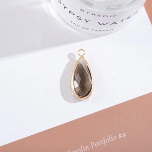 Macro shot of faceted teardrop-shaped smoky crystal pendant with gold-plated metal border
