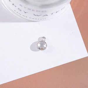 Macro detail of a silver round pendant with a multi-faceted clear crystal stone inlay