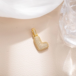 Macro shot of micro-pave zircon letter L pendant with gold finish on leather