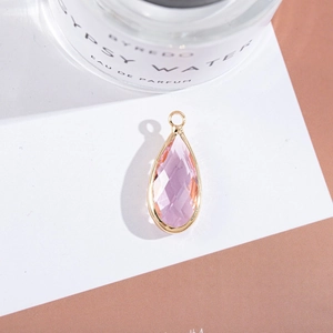 Close-up of pink faceted teardrop pendant with gold metal frame for DIY jewelry making