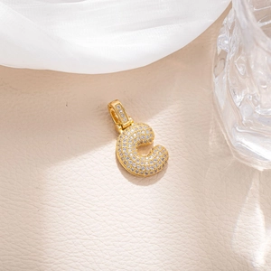 Close-up of golden letter C pendant with micro-paved sparkling cubic zirconia stones