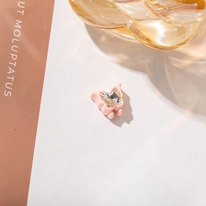 Detailed view of pink resin butterfly hair clip with clear crystal inlay on warm background