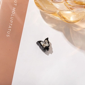 Detailed view of a glossy black butterfly hair clip with a large central crystal