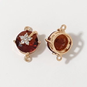 Detailed macro view of a gold-plated flower connector with a red gemstone for jewelry making