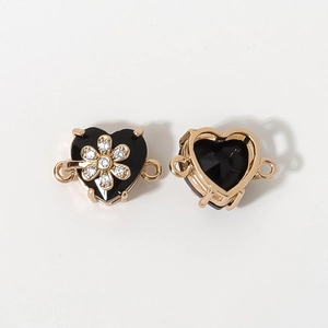 Vista de conectores de joyería en forma de corazón dorado con gemas negras y detalle de flores