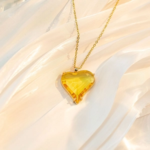 Detailaufnahme eines herzförmigen gelben Kristallanhängers an einer goldenen Kette