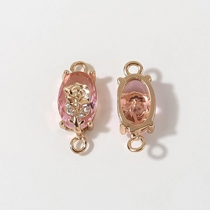 Macro-opname van vergulde rozenbedeltjes met roze kristallen en lussen voor DIY-sieraden