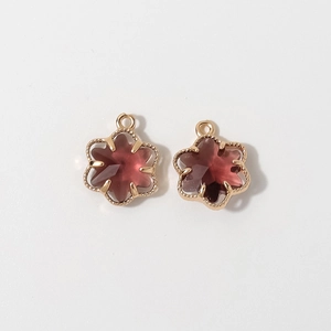 Detailed view of 12mm gold-plated flower pendants with deep red faceted crystal stones