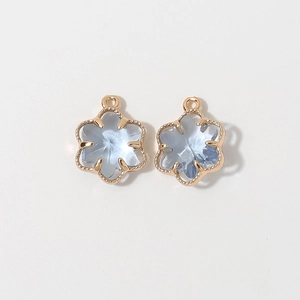 Close-up of 12mm light blue floral charms with gold plated borders and hanging loops
