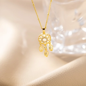Macro shot of gold dreamcatcher pendant with leaf charms on a titanium steel bead chain
