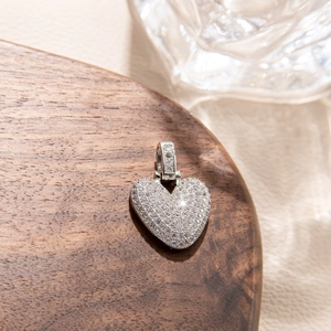 Macro shot of silver heart pendant with micro-paved zircons on elegant wooden tray