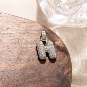 Macro view of iced out bubble letter H pendant with micro paved sparkling zircon stones