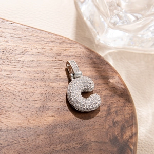 Macro shot of micro-paved zircon lowercase letter c pendant in silver-tone metal
