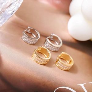 Macro-opname van zilveren en gouden oorringen met drie rijen micro-pave zirkonia