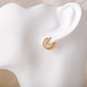 Detailweergave van gouden oorbellen met drie rijen pavé-zirkonen op oormodel