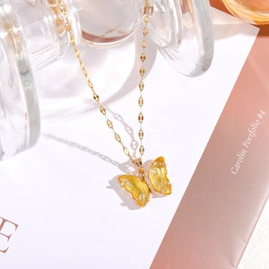 Detailansicht einer goldenen Titan-Halskette mit einem gelben Schmetterlingsanhänger