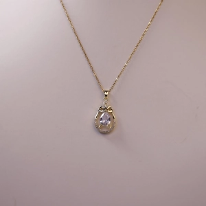 Detailed close-up of a pear-cut crystal teardrop pendant with a delicate bow design
