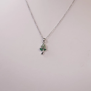 Primer plano de un collar con colgante de tulipán plateado y piedras verdes claras