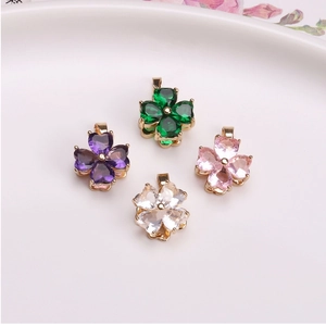 Dettaglio di ciondoli a quadrifoglio con zircone a cuore in verde, viola, rosa e bianco