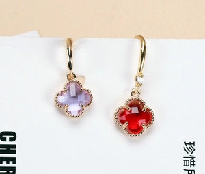 Detail of four leaf clover earrings with purple and red crystals and golden finish