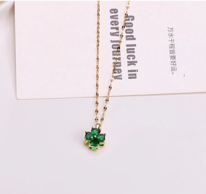 Dettaglio di un ciondolo a quadrifoglio dorato rotante con cristalli di zirconia verde