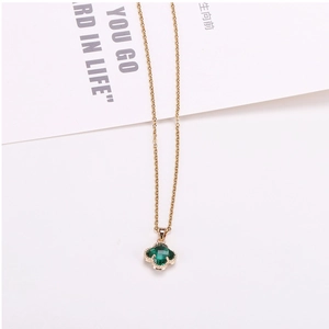 Close-up of golden clover necklace with faceted emerald green crystal and beaded edge