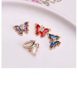 Detail of four crystal butterfly pendants in purple red blue and clear on a ceramic plate