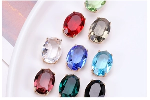 Macro shot of colorful oval crystal pendants with gold-plated brass settings in a tray
