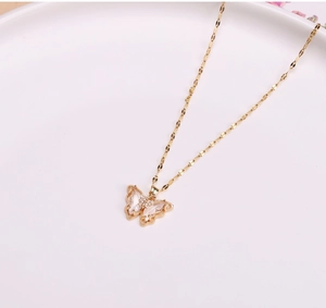 Macro detail of gold butterfly pendant with translucent wings and pavé crystals on chain