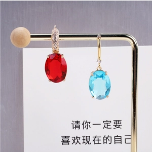 Detailed view of red and blue oval crystal earrings with gold plating and fine inlay