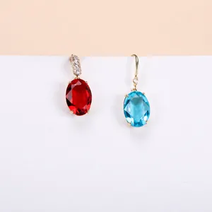 Detailed close-up of gold-plated oval crystal pendants in red and blue for jewelry making