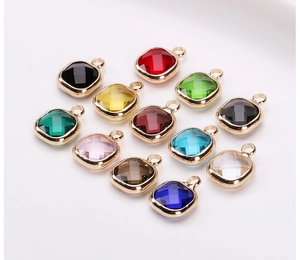 Macro shot of 12 colorful square faceted crystal pendants with gold plated metal edges