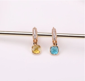 Detail of gold-plated drop earrings featuring square cut yellow and blue crystals