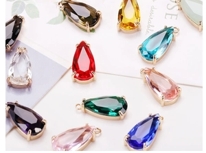 Detailed macro shot of assorted colorful teardrop glass pendants with gold claw settings