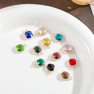 Gold plated faceted square crystal pendants in various colors displayed on a white plate