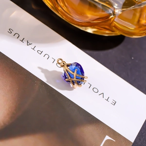 Nahaufnahme eines herzförmigen blauen Kristallanhängers mit goldenem Metallrahmen