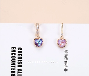 Detail of asymmetrical heart crystal earrings with blue and pink pendants in gold settings