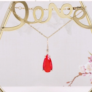 Macro detail of pear-shaped red crystal pendant hanging on golden metal love rack