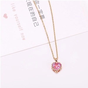 Close-up of pink heart crystal pendant with intricate gold filigree border and gold chain